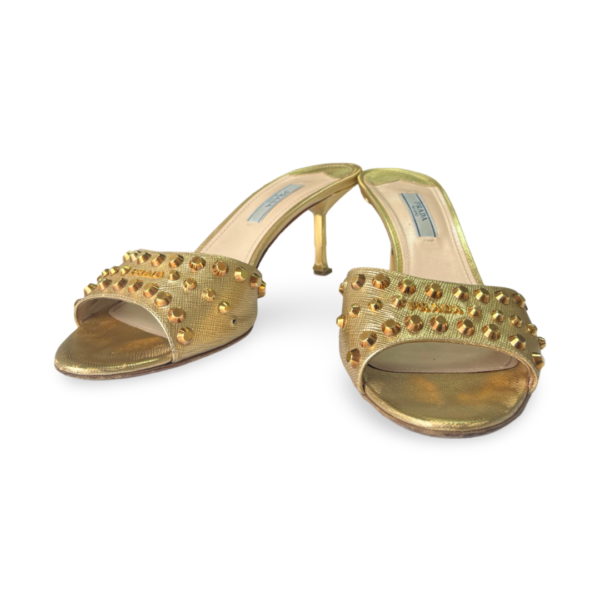 Gold stiletto heeled sandals with a studded design on the straps.