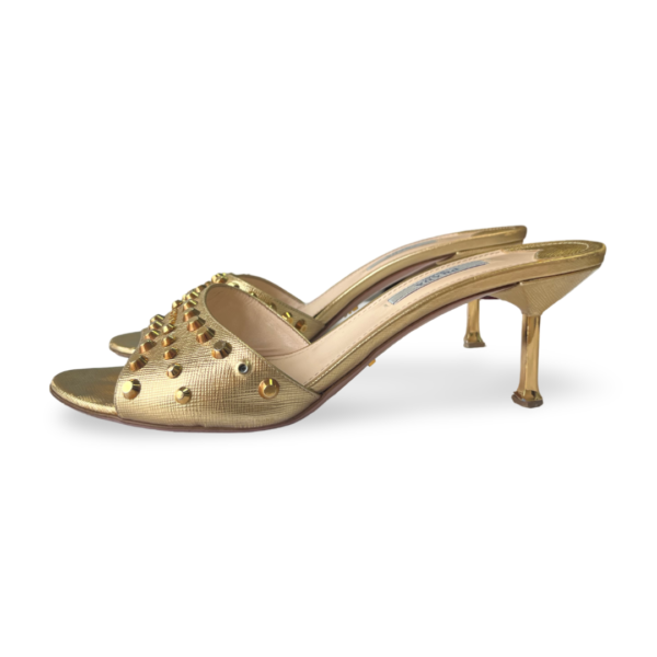 Gold slip-on sandals with stiletto heels and decorative studs on the upper.